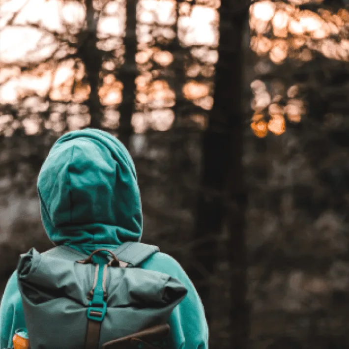 Personne faisant de la randonnée avec un sac à dos et un sweat pour montrer qu'il faut se couvrir dans la fôret.