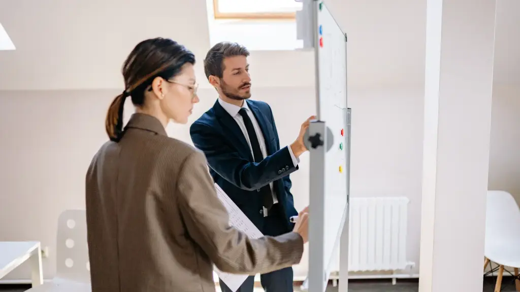 Deux collègues qui discutent devant un tableau blanc, dans un bureau lumineux