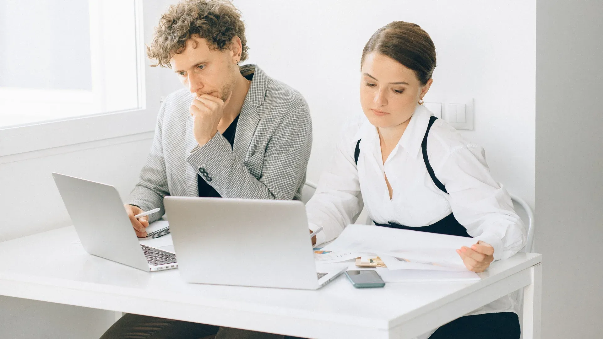 Dirigeant de PME qui compare deux devis de création de site internet à son bureau