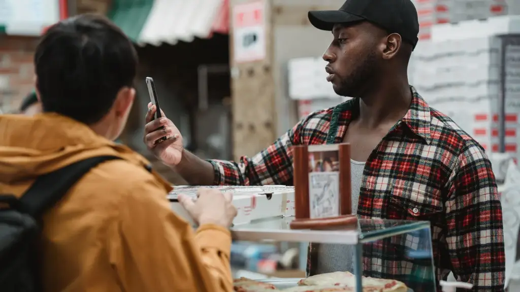 Deux hommes qui regardent un smartphone devant un étal de marché
