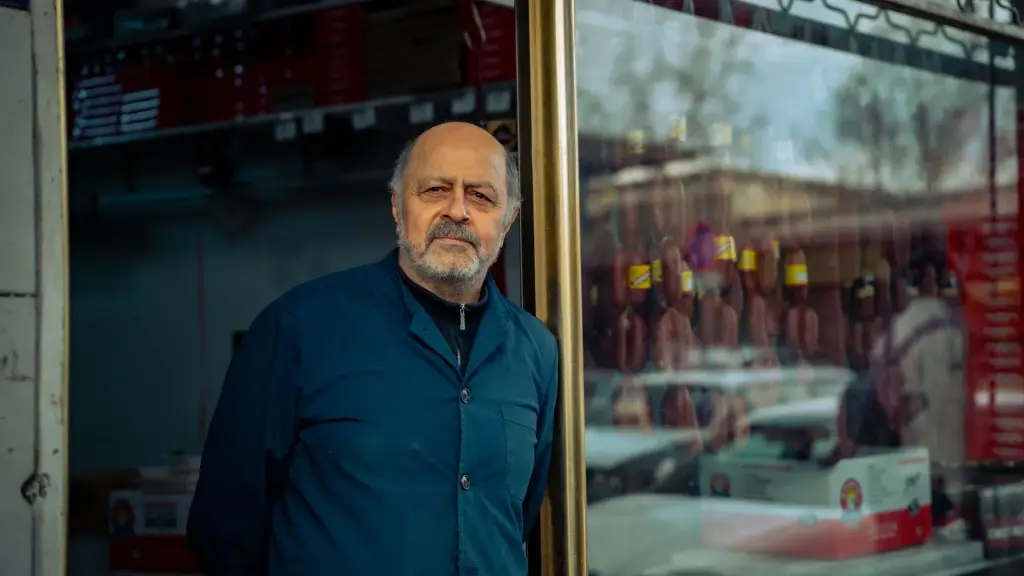 Commerçant devant sa vitrine qui s'interroge sur l'ancien logo de son entreprise