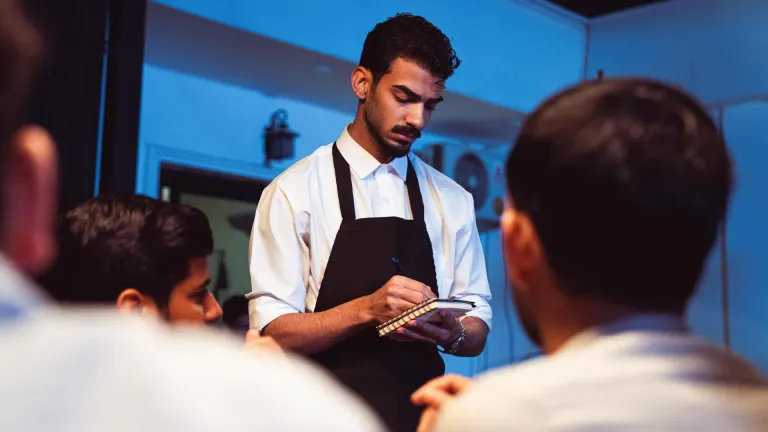 Restaurateur accueille ses clients dans la salle de son restaurant