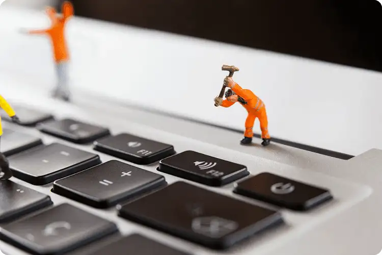 Figurines d'ouvriers miniatures réparant le clavier d'un ordinateur portable